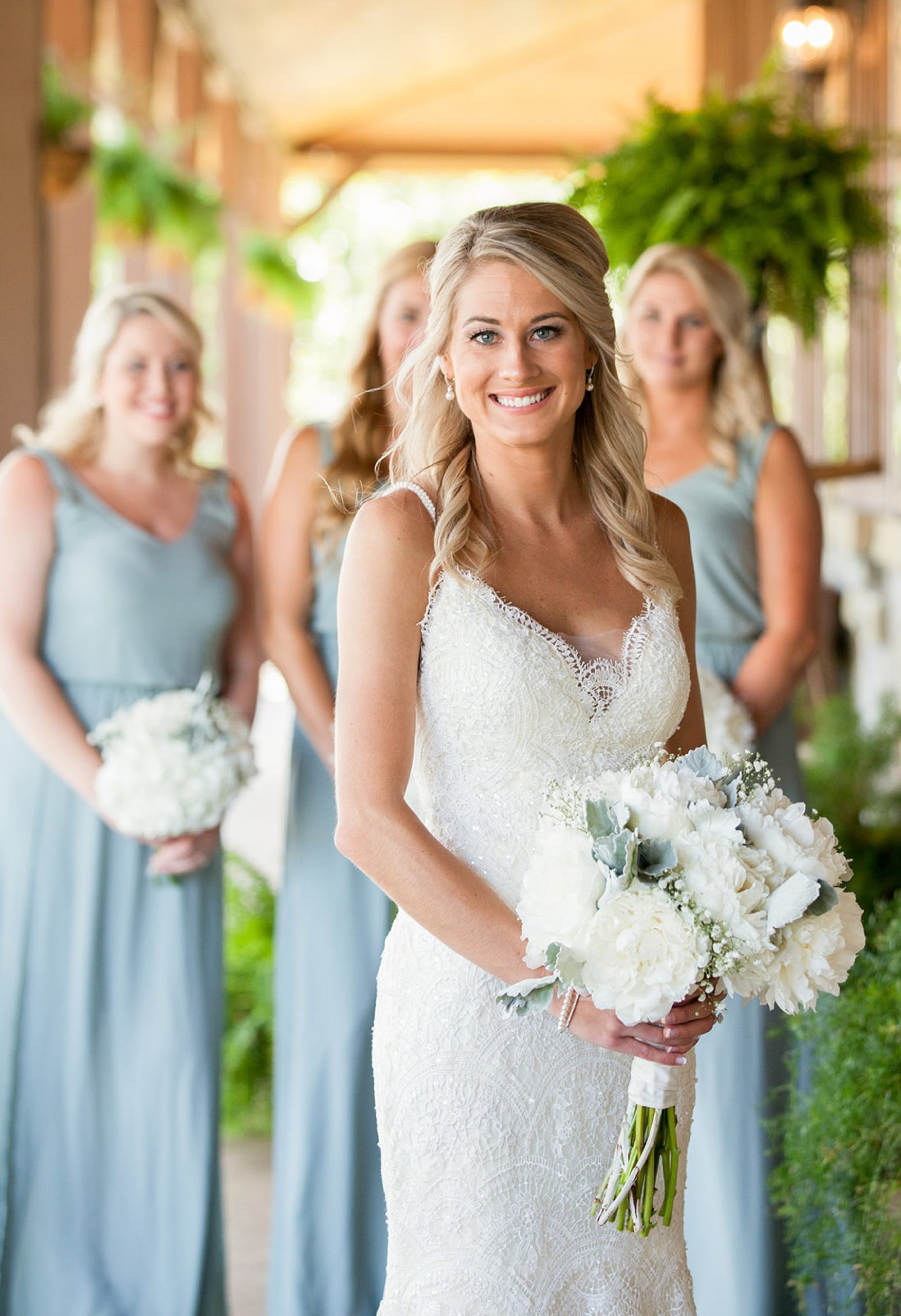 Bride standing with bridesmaids in dusty blue in the background