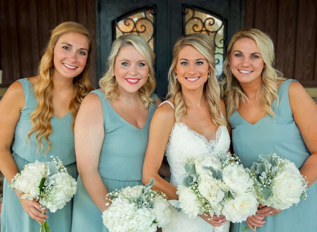 Bride standing with bridesmaids in turquoise dresses