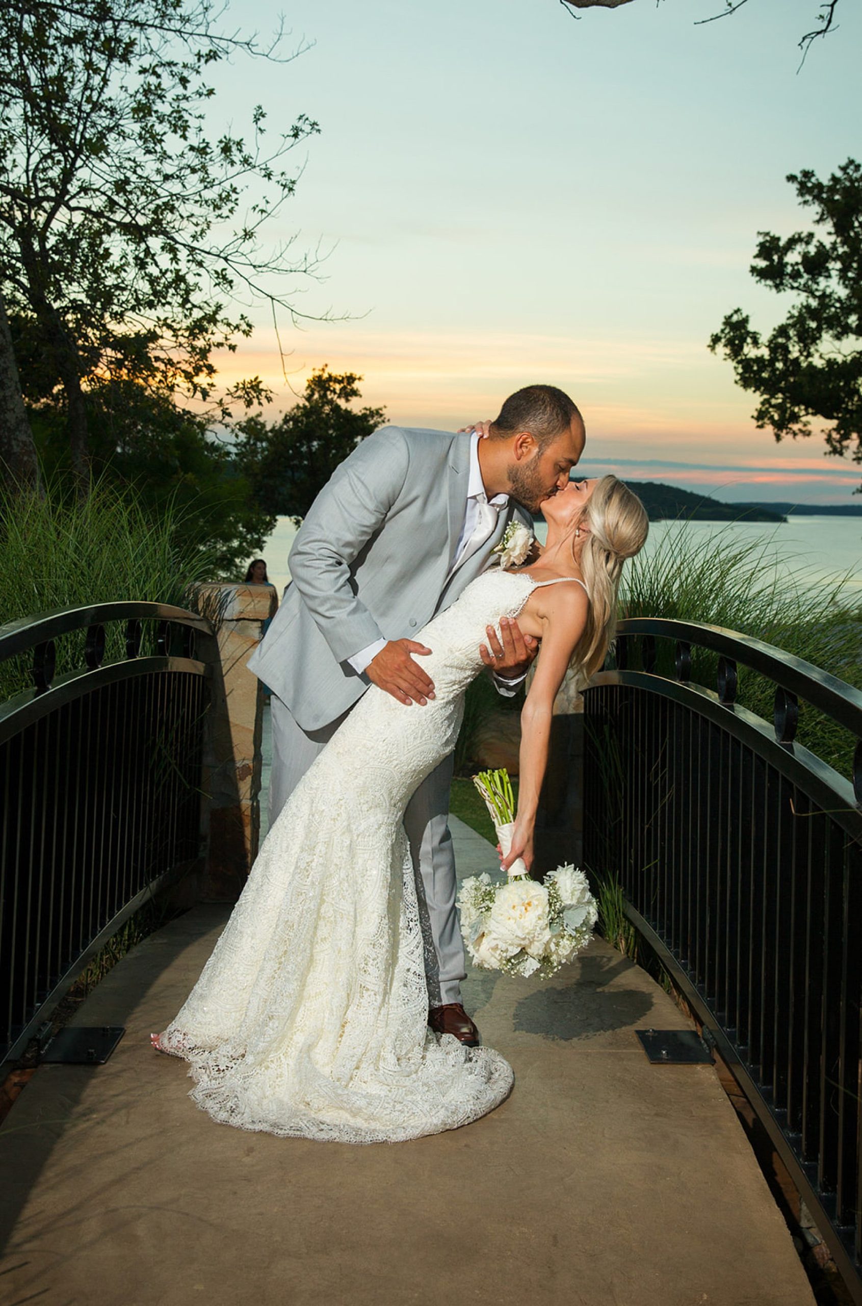 Groom dipping bride on bride by lake at The Springs Event Center wedding