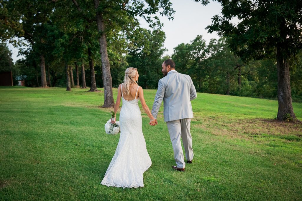 Bride and groom walking away on grass at The Springs wedding event center