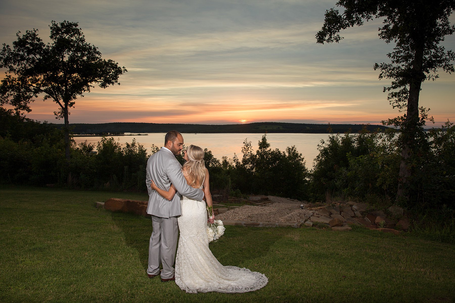 Bride and groom looking at each other in front of lake sunset at The Springs wedding event center