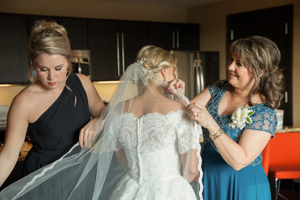 Mother of bride and bridesmaid adjust brides veil