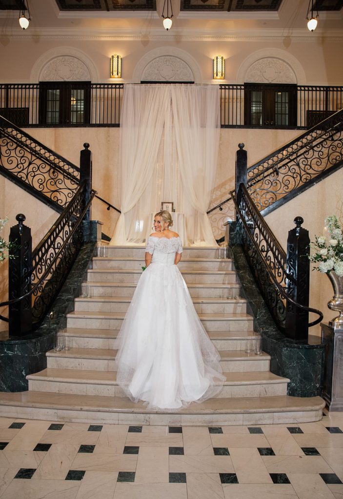 Bride standing on stairs at The Mayo Hotel looking over shoulder